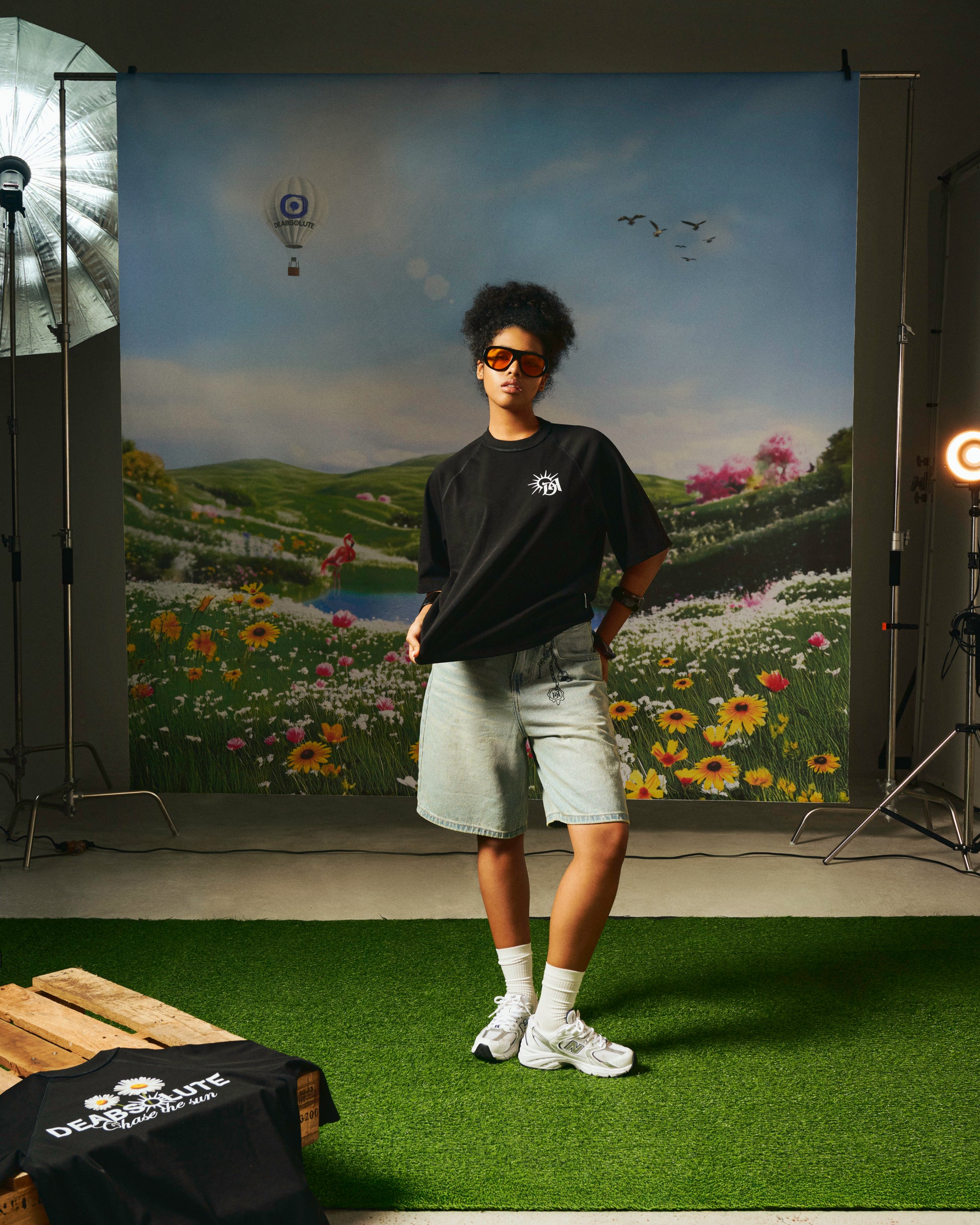 Person wearing a black t-shirt with a logo, standing in front of a scenic backdrop in a studio setting.
