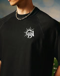 Black t-shirt with a white logo on a person wearing a chain necklace.